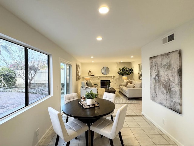 dining room with recessed lighting, baseboards, a brick fireplace, and light tile patterned flooring