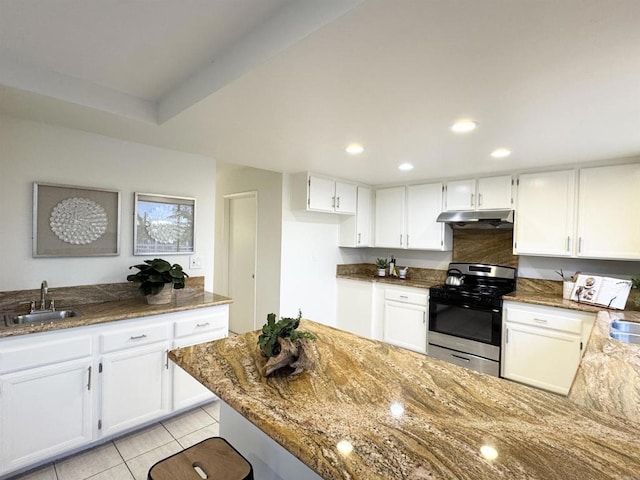 kitchen with under cabinet range hood, stone countertops, stainless steel range with gas stovetop, and a sink