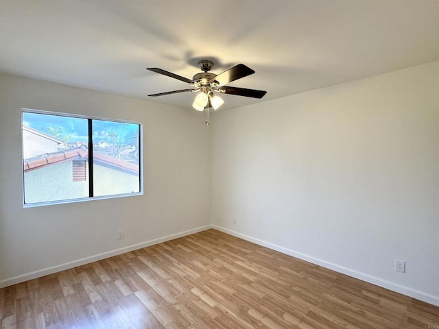 spare room featuring ceiling fan, light wood-type flooring, and baseboards