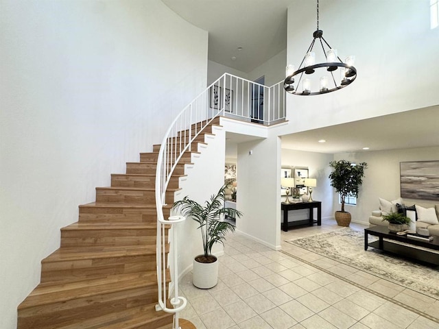 stairway with tile patterned floors, baseboards, a notable chandelier, and a towering ceiling