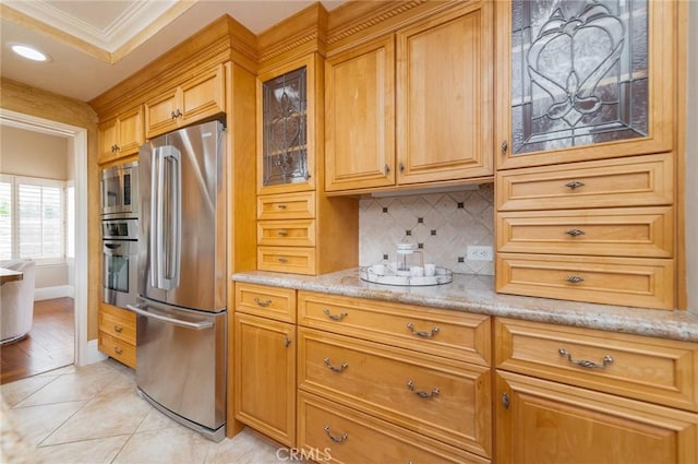 kitchen with light stone counters, tasteful backsplash, appliances with stainless steel finishes, light tile patterned floors, and glass insert cabinets