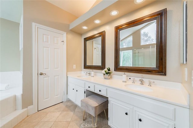 full bath with a sink, a bath, double vanity, and tile patterned flooring