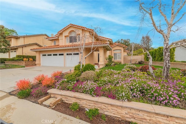 mediterranean / spanish home with fence, driveway, an attached garage, stucco siding, and a tiled roof