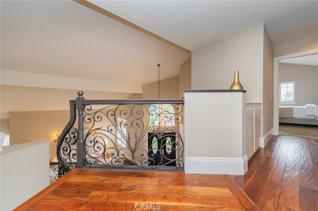 stairs with wood finished floors, baseboards, and vaulted ceiling