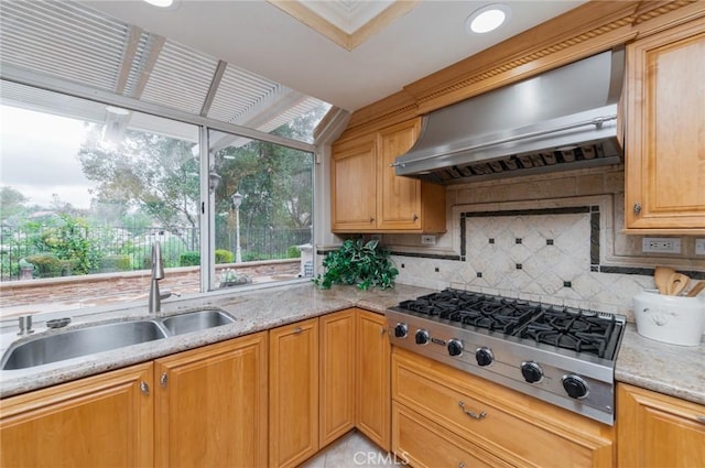 kitchen featuring a sink, tasteful backsplash, wall chimney exhaust hood, light stone countertops, and stainless steel gas cooktop