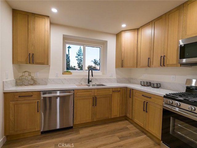 kitchen featuring recessed lighting, appliances with stainless steel finishes, light wood-type flooring, and a sink