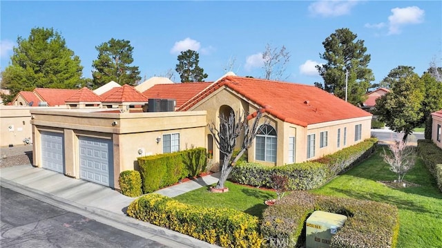 mediterranean / spanish house with a front yard, concrete driveway, a garage, and stucco siding