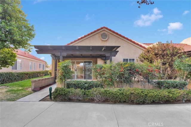 view of front of property featuring a tiled roof, a pergola, and stucco siding