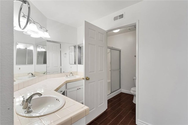 bathroom with a stall shower, toilet, wood tiled floor, and a sink