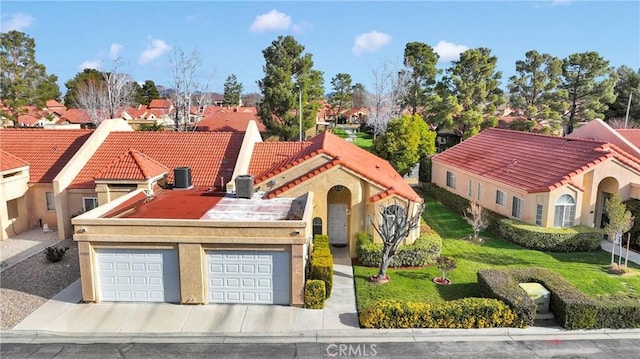 mediterranean / spanish house featuring a tile roof, central AC unit, a residential view, and stucco siding