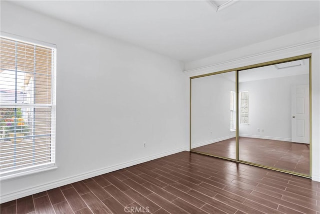 unfurnished bedroom featuring a closet, baseboards, and wood finished floors