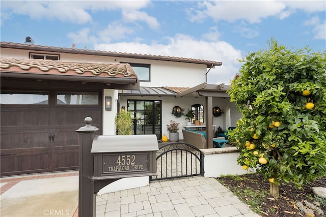 view of front of home with stucco siding, a tiled roof, a garage, and a gate