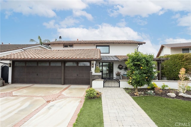 view of front of home with a tile roof, stucco siding, driveway, an attached garage, and a gate