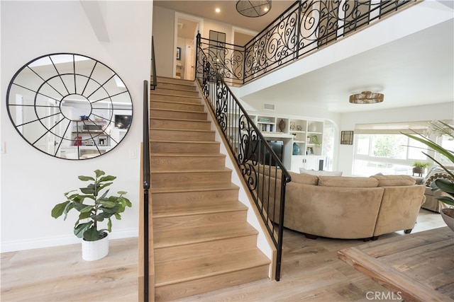 stairway featuring visible vents, baseboards, recessed lighting, a towering ceiling, and wood finished floors