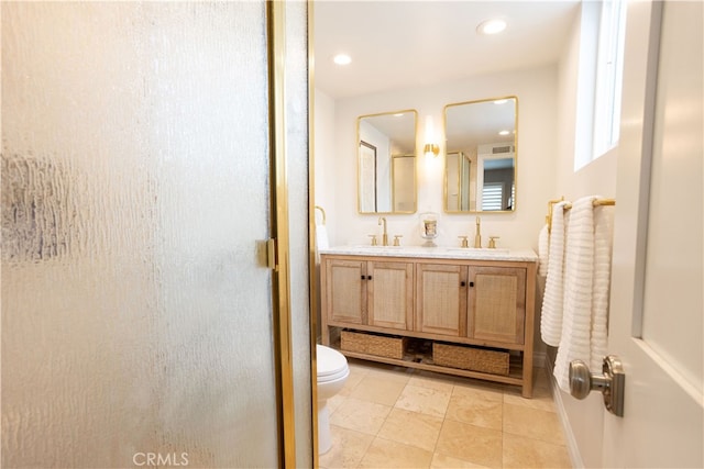 full bath featuring double vanity, toilet, a shower with door, and a sink