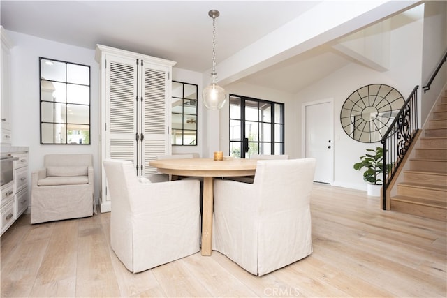 dining room featuring lofted ceiling, stairs, and light wood-style floors