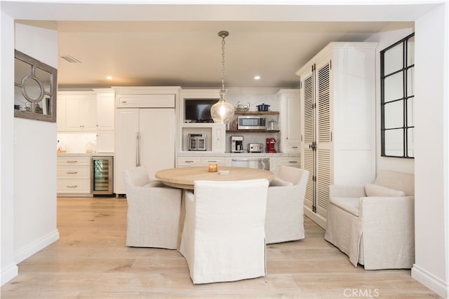 kitchen featuring paneled fridge, light wood-style flooring, stainless steel microwave, recessed lighting, and wine cooler