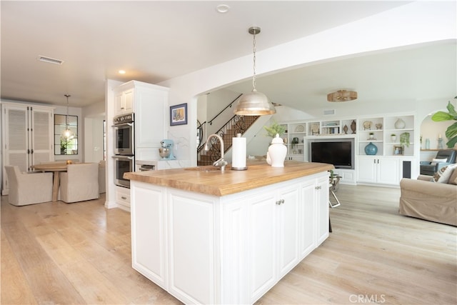 kitchen with a sink, open floor plan, visible vents, and stainless steel double oven