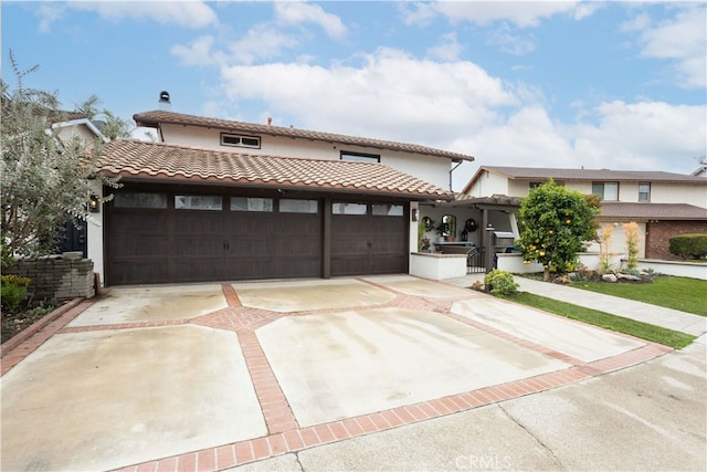 view of front of house with driveway, an outdoor kitchen, an attached garage, and a tiled roof