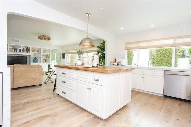 kitchen featuring light wood-style flooring, arched walkways, a sink, dishwasher, and butcher block counters