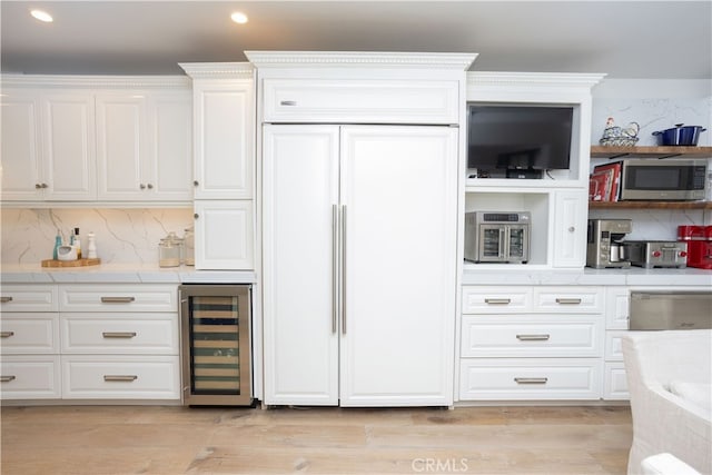 kitchen with tasteful backsplash, stainless steel microwave, beverage cooler, paneled built in fridge, and white cabinets