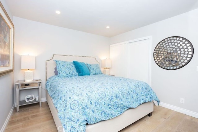 bedroom featuring light wood-style flooring, recessed lighting, baseboards, and a closet