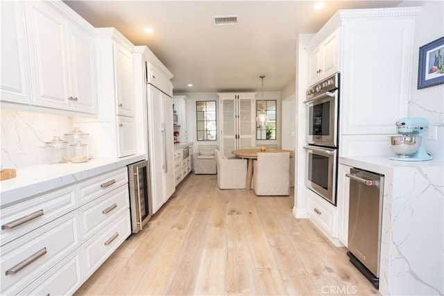 kitchen featuring stainless steel double oven, visible vents, wine cooler, and white cabinets