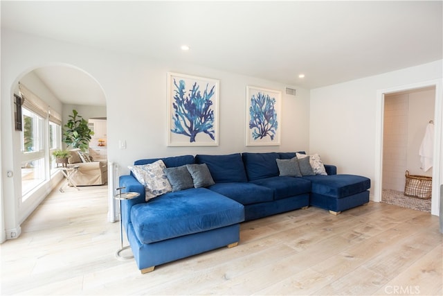 living room featuring visible vents, light wood-style flooring, recessed lighting, and arched walkways