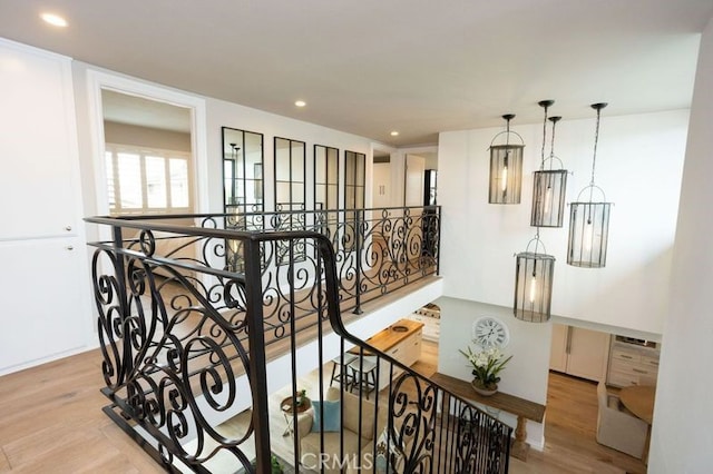 hallway with an upstairs landing, wood finished floors, and recessed lighting