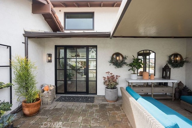 entrance to property with an outdoor living space, a patio area, and stucco siding