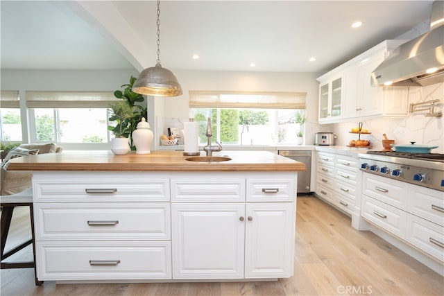 kitchen with stainless steel appliances, decorative backsplash, glass insert cabinets, white cabinetry, and wall chimney exhaust hood