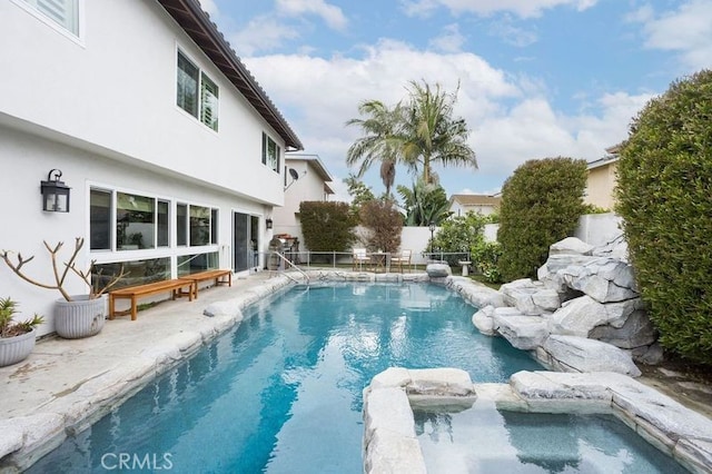 view of pool featuring a pool with connected hot tub and fence