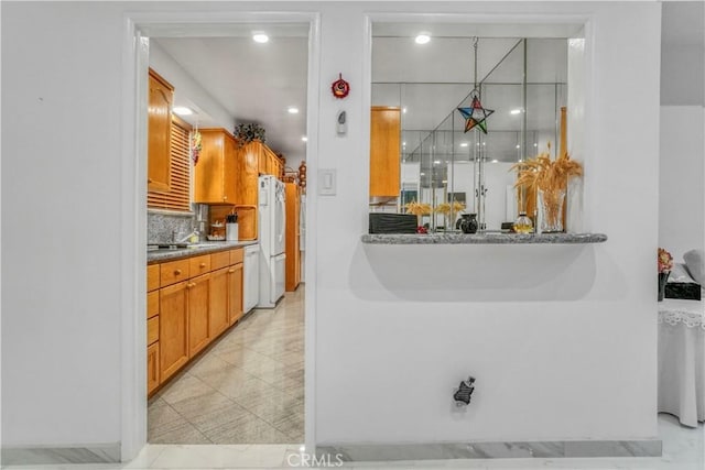 kitchen with decorative backsplash, white appliances, and brown cabinetry