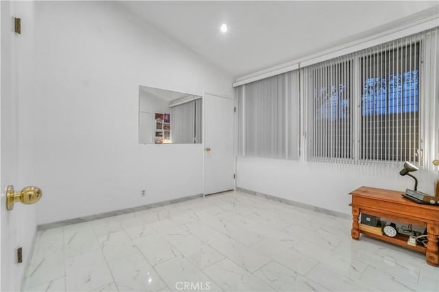 spare room with lofted ceiling, baseboards, and marble finish floor