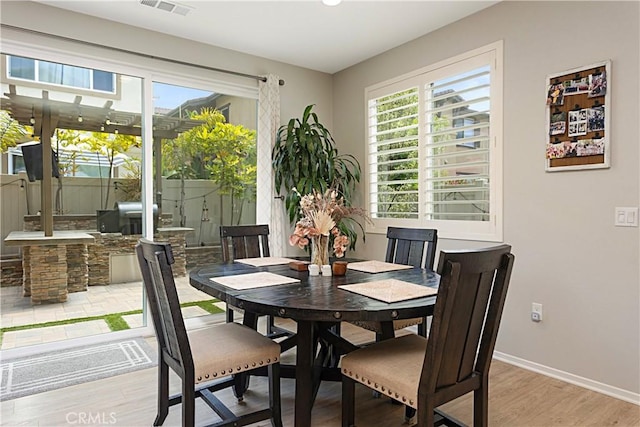 dining space featuring visible vents, baseboards, and light wood finished floors