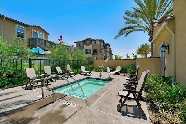 view of pool with a patio, fence, and a hot tub