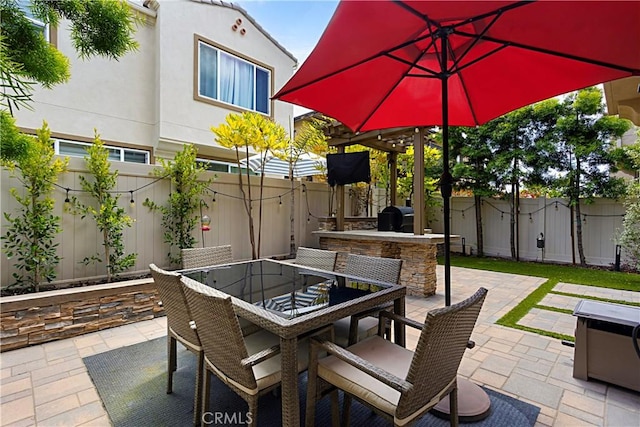 view of patio with a fenced backyard, grilling area, outdoor dining space, and exterior kitchen