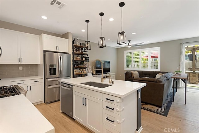 kitchen featuring light countertops, light wood-style flooring, stainless steel appliances, a ceiling fan, and a sink