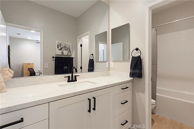 bathroom featuring vanity, toilet, wood finished floors, and shower / tub combo with curtain