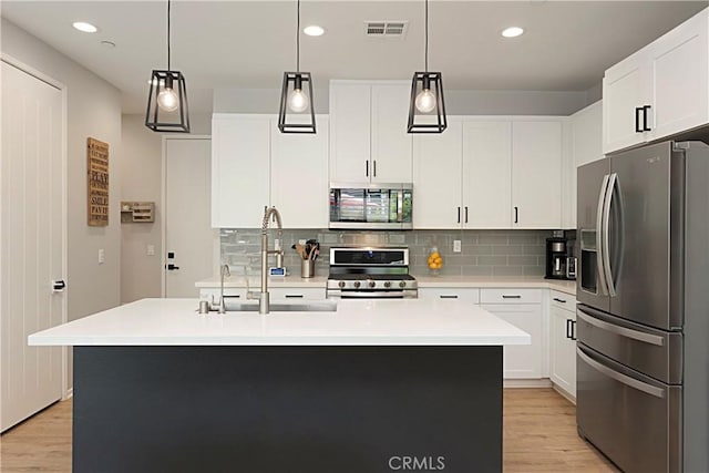 kitchen with visible vents, light countertops, decorative backsplash, appliances with stainless steel finishes, and a sink