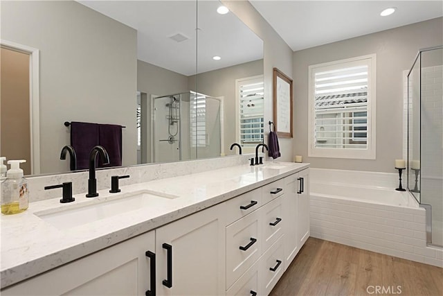 full bathroom featuring a stall shower, a sink, wood finished floors, double vanity, and a bath