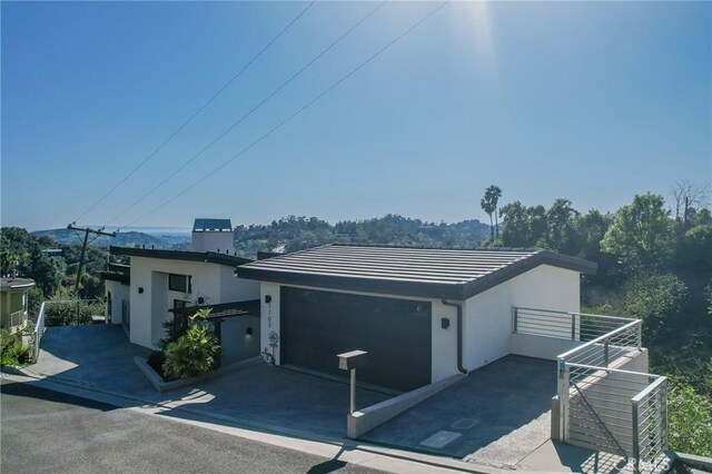 view of front facade with a tiled roof, a garage, driveway, and stucco siding