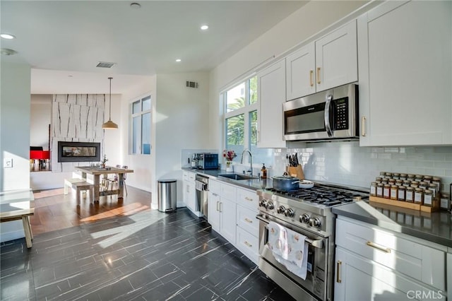 kitchen with visible vents, a sink, decorative backsplash, white cabinets, and appliances with stainless steel finishes