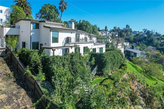 back of property featuring a balcony, a chimney, and stucco siding