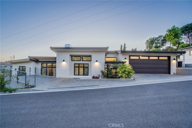 view of front of home featuring an attached garage, driveway, and stucco siding