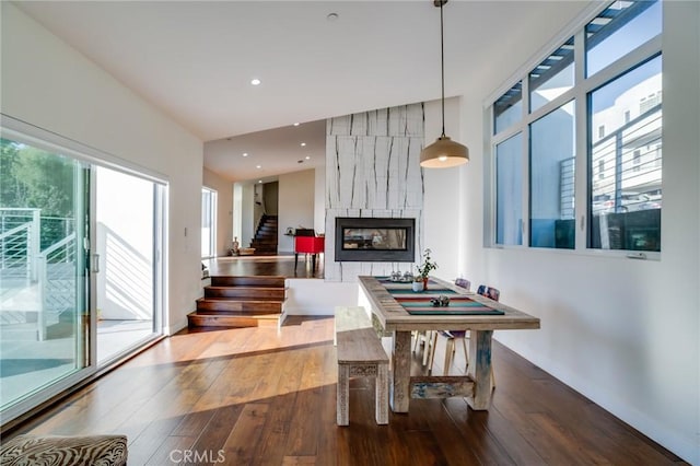 dining room featuring plenty of natural light, a fireplace, stairway, and hardwood / wood-style floors