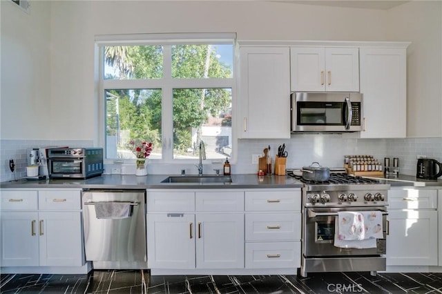 kitchen featuring a sink, stainless steel appliances, plenty of natural light, and white cabinets