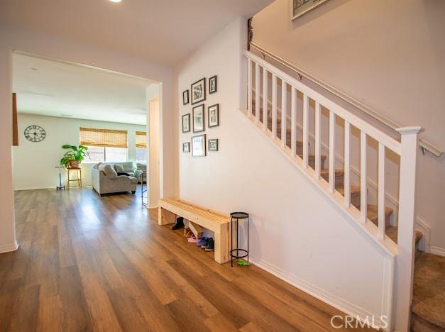 hallway featuring baseboards, wood finished floors, and stairs