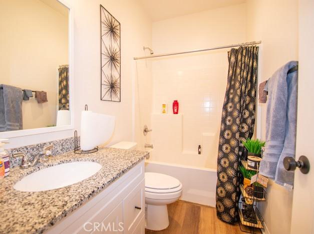 bathroom featuring shower / bath combo with shower curtain, toilet, vanity, and wood finished floors