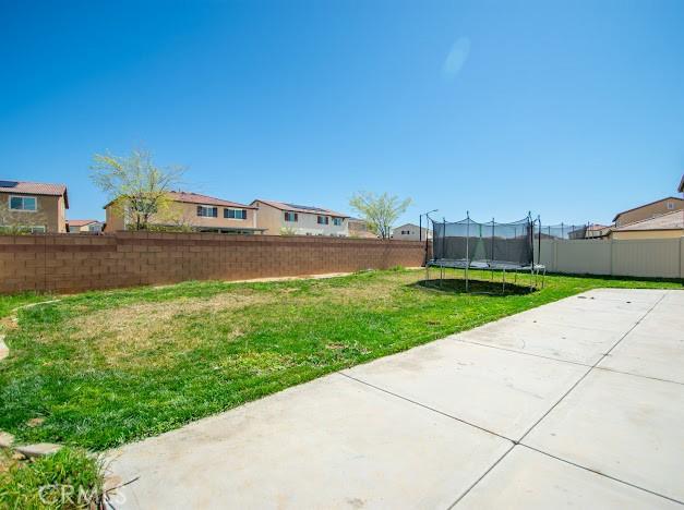 view of yard featuring a patio, a trampoline, and fence
